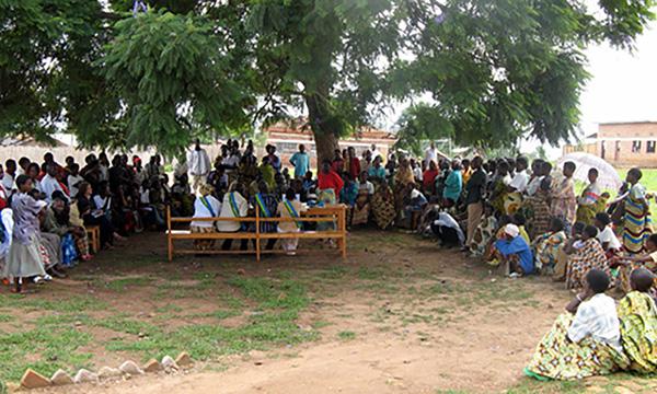 large group of people holding an outdoor court session under a tree